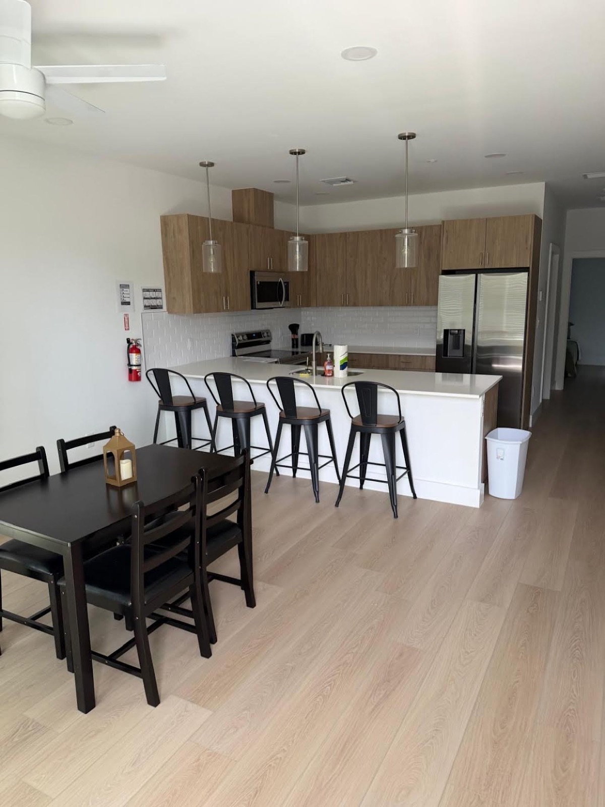 Sober living kitchen and dining — modern open-plan layout with island, barstools, and wood cabinetry